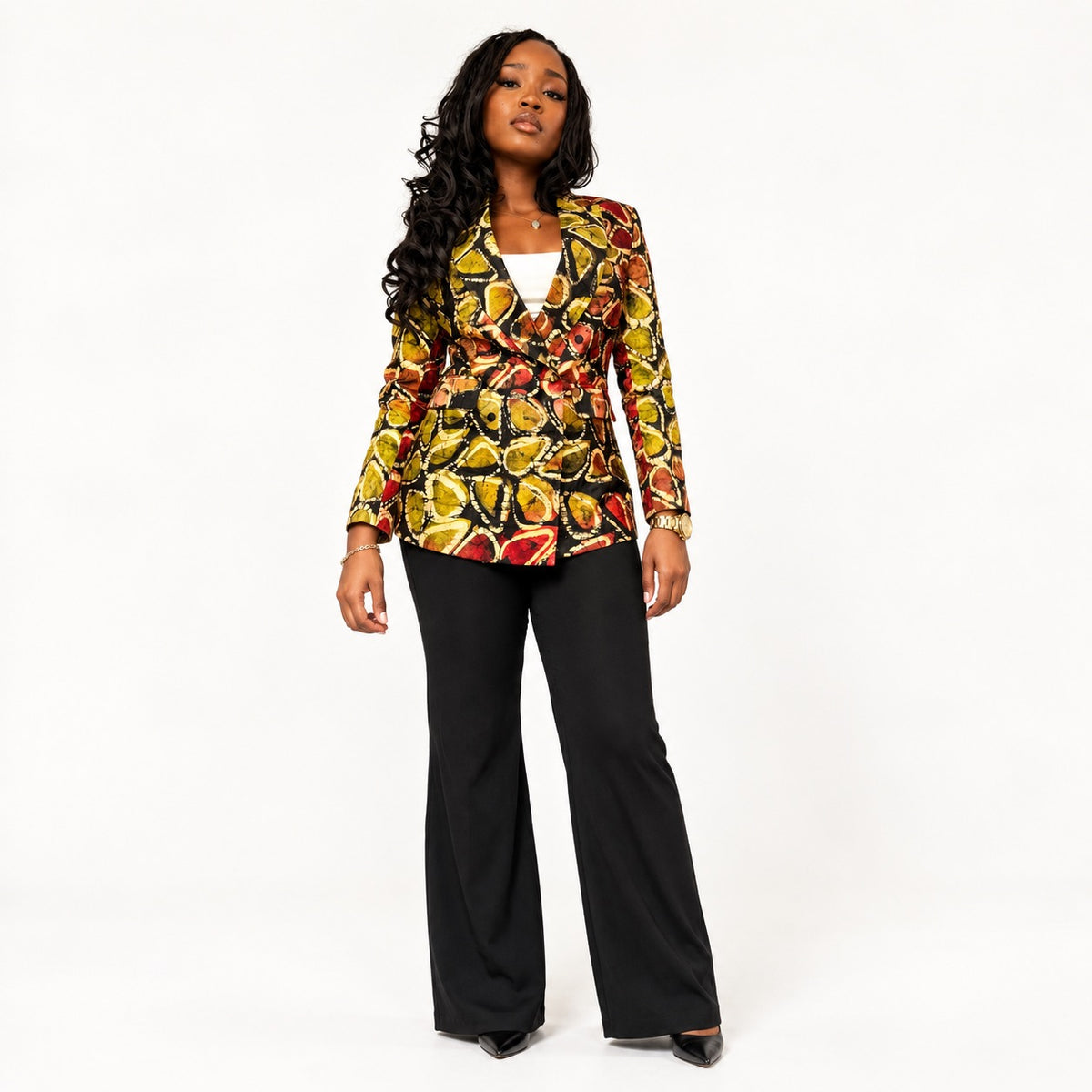 Model wearing a patterned double-breasted blazer in olive, gold, and rust tones with black trousers